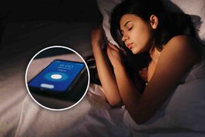 Cellulare con sveglia e donna dormiente nel letto